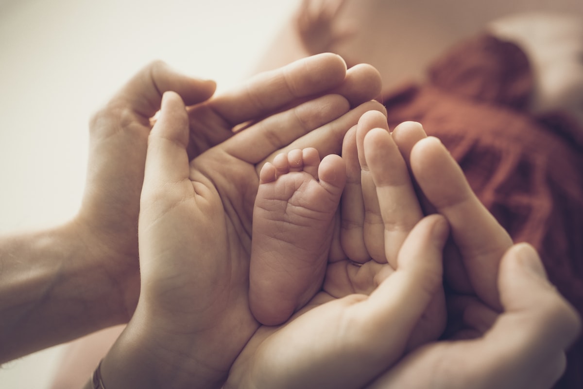 A parent gently holding a baby's hand.
